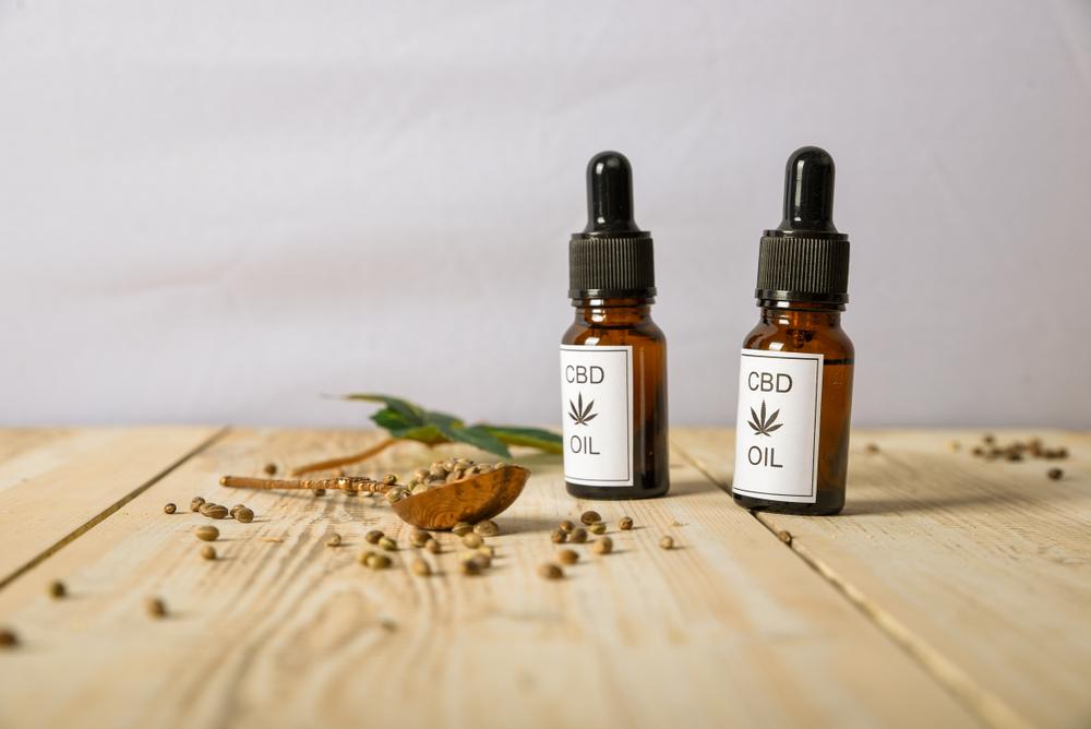 wo dropper bottles of CBD oil with hemp seeds on a wooden table top